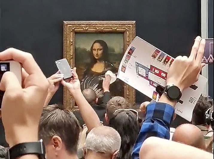 A security guard cleans smeared cream from the glass protecting the Mona Lisa at the Louvre Museum, in Paris, France, Sunday, May 29, 2022. A man seemingly disguised as an old woman in a wheelchair threw a piece of cake at the glass protecting the painting and shouted at people to think of planet Earth.  (@Klevisl007 via AP)