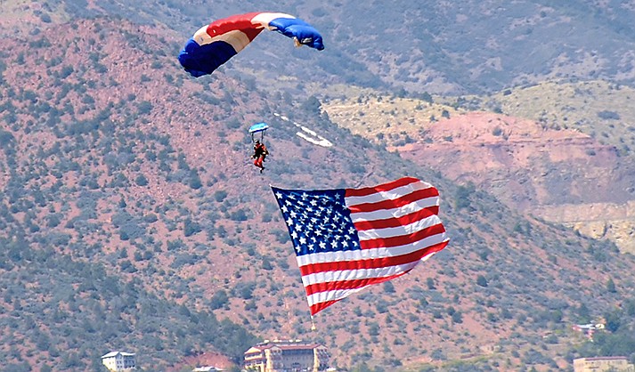 A skydiver lands at the Cottonwood Airport on Sept. 11, 2015, in a parachute while flying an American flag. The Town of Jerome can be seen in the distance. The Cottonwood City Council adopted minimal operating standards for commercial skydiving operations Tuesday, June 7, 2022. (VVN/File/Vyto Starinskas)