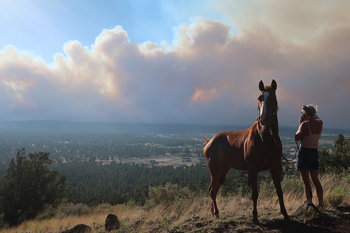 Janetta Kathleen and her horse, Squish, watch as smoke rises above neighborhoods on the outskirts of Flagstaff, Sunday, June 12, casts a glow above neighborhoods. Evacuations have been ordered for homes in the area. Authorities say firefighters are responding to the wildfire about six miles north of Flagstaff that has forced evacuations. (Felicia Fonseca/AP)