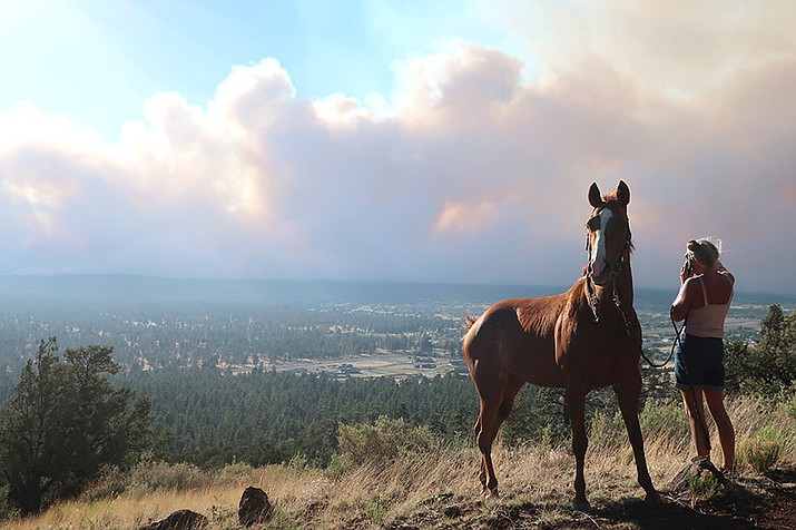 Janetta Kathleen and her horse, Squish, watch as smoke rises above neighborhoods on the outskirts of Flagstaff June 12. Authorities say firefighters are responding to two wildfires about six miles northeast of Flagstaff that have forced evacuations. (AP Photo/Felicia Fonseca)