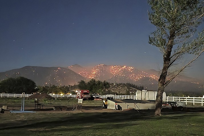 This Monday, June 13, 2022, photo provided by Wendy Pettay shows flames twinkling on a mountain on the outskirts of Flagstaff, Arizona. More favorable wind aided firefighters battling the blaze on Tuesday. (Wendy Pettay via AP)