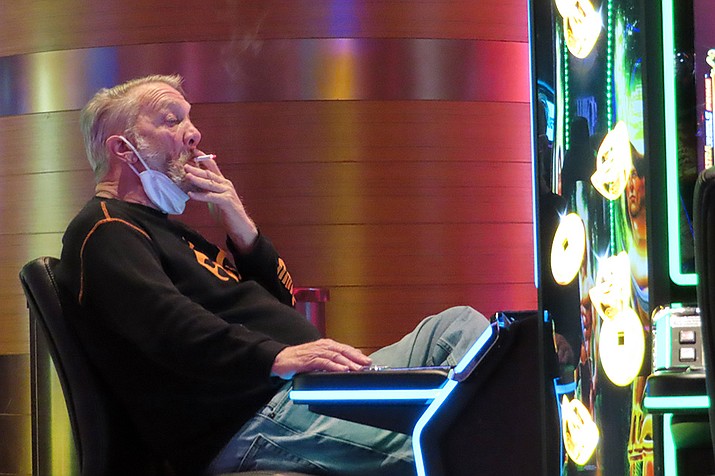 A man smokes while playing a slot machine at the Ocean Casino Resort in Atlantic City, N.J., on Feb. 10, 2022. A report issued Friday, June 17, 2022, by a Las Vegas gambling research company suggested that ending smoking in casinos will not result in significant financial harm to the businesses.. (Wayne Parry, AP File)