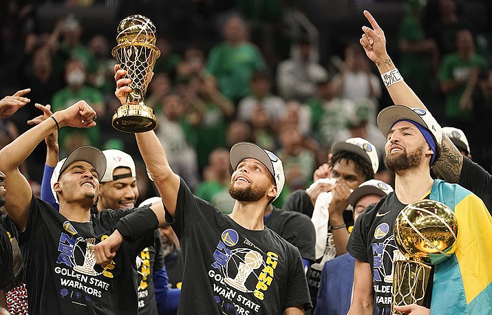 Golden State Warriors guard Stephen Curry, center, holds up the Bill Russell Trophy for most valuable player after the Warriors defeated the Boston Celtics in Game 6 to win basketball's NBA Finals championship, Thursday, June 16, 2022, in Boston. (Steven Senne/AP)