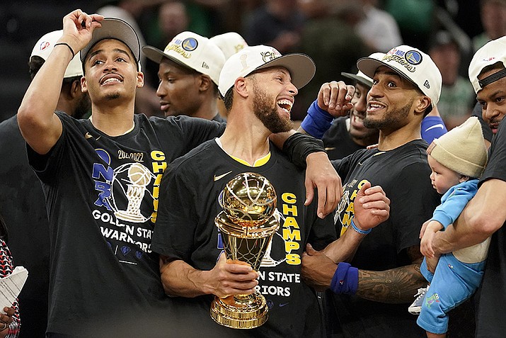Golden State Warriors guard Stephen Curry, center, celebrates with teammates as he holds the Bill Russell Trophy for Most Valuable Player after the Warriors beat the Boston Celtics in Game 6 to win basketball's NBA Finals, Thursday, June 16, 2022, in Boston. (Steven Senne/AP)