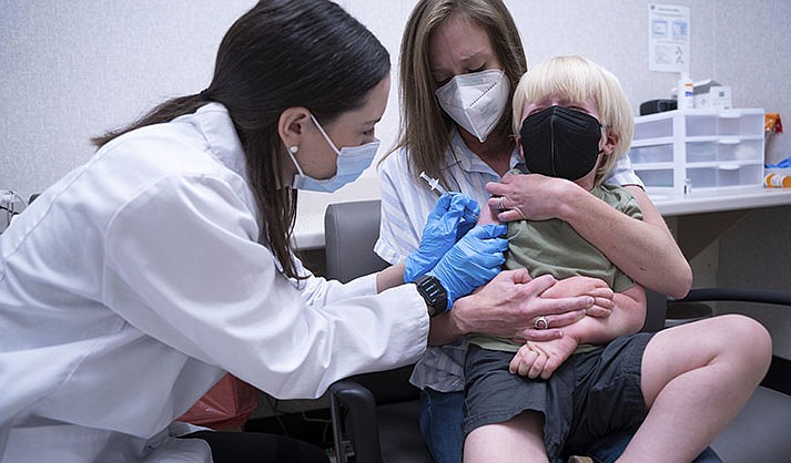 Pharmacist Kaitlin Harring, left, administers a Moderna COVID-19 vaccination to 3-year-old Fletcher Pack, while he sits on the lap of his mother, McKenzie Pack, at Walgreens pharmacy Monday, June 20, 2022, in Lexington, South Carolina. It marked the first day COVID-19 vaccinations were made available to children under 5 in the United States. (AP Photo/Sean Rayford)