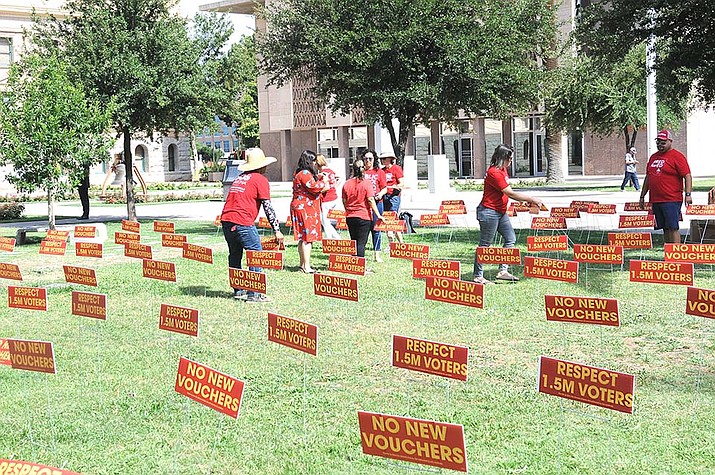 Members of Save Our Schools Arizona erect signs on the lawn at the State Capitol Wednesday, June 22, 2022, urging lawmakers to reject universal vouchers and honor the will of voters who four years ago voting against expansion. (Howard Fischer/Courtesy)