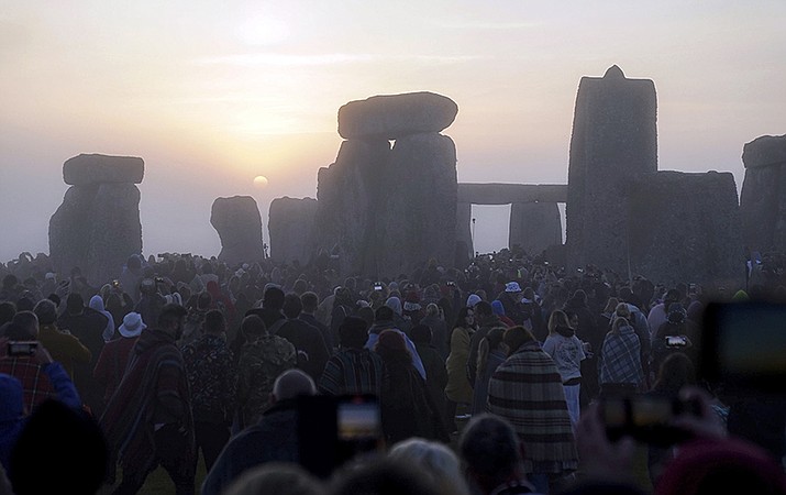 The sun begins to rise above the stones as people gather at sunrise to take part in the Summer Solstice festivities at Stonehenge in Wiltshire, England, Tuesday, June 21, 2022. After two years of closure due to the COVID-19 pandemic, Stonehenge reopened Monday for the Summer Solstice celebrations. (Andrew Matthews/PA via AP)