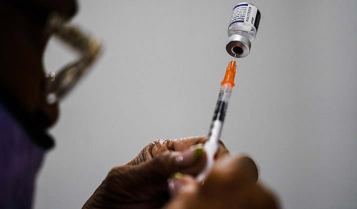 A syringe is prepared with the Pfizer COVID-19 vaccine at a vaccination clinic at the Keystone First Wellness Center in Chester, Pa., Dec. 15, 2021.  Pfizer says tweaking its COVID-19 vaccine to better target the omicron variant is safe and boosts protection. Saturday, June 25, 2022 announcement comes just days before regulators debate whether to offer Americans updated booster shots this fall. (AP Photo/Matt Rourke, File)