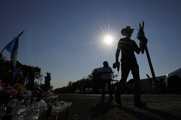 Roberto Marquez adds a wooden cross to a makeshift memorial at the site where officials more than 50 people dead in an abandoned semitrailer containing suspected migrants, Thursday, June 30, 2022, in San Antonio. (AP Photo/Eric Gay)