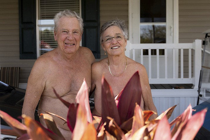 Bill and Misty Katz pose in front of their home at Nature’s Resort on March 16, 2022, in Elsa, Texas. Bright orange letters welcome you to “Nature’s Resort.” Nothing looks amiss, except for what’s missing — clothing. (Jeremy Lindenfeld/Religion News Service)