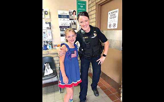 Isabella Hennard, 9, from Colorado visits with Williams Police Officer White after presenting “survival kits” for law enforcement officers. (Photo/WPD)