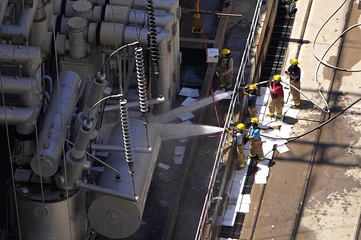 Firefighters spray water after a fire on the Arizona side of the Hoover Dam, July 19 near Boulder City, Nev. Officials say no one was injured when a transformer at Hoover Dam briefly caught fire. (AP Photo/John Locher)