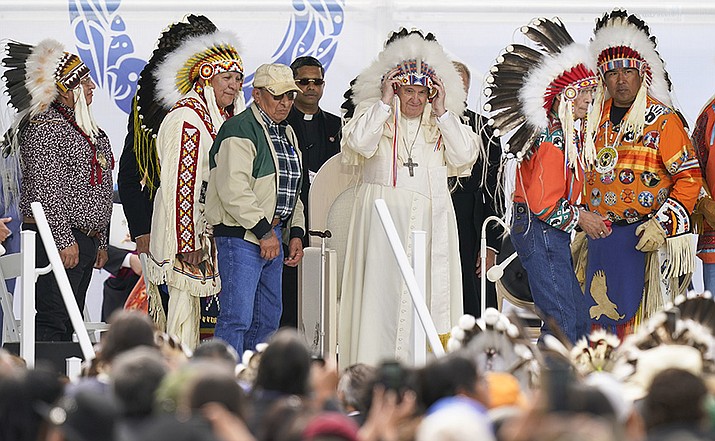Pope Francis dons a headdress during a visit with Indigenous peoples at Maskwaci, the former Ermineskin Residential School, Monday, July 25, 2022, in Maskwacis, Alberta. Pope Francis traveled to Canada to apologize to Indigenous peoples for the abuses committed by Catholic missionaries in the country's notorious residential schools. (AP Photo/Eric Gay)