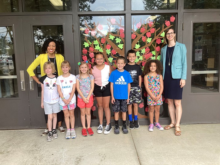 State Superintendent of Public Instruction Kathy Hoffman  (far right in picture) with new Abia Judd Elementary Principal Rachel Chunglo on the far left between a group of seven third- and fourth-graders standing before the school’s character trait chart on the front window. (Nanci Hutson/Courier)
