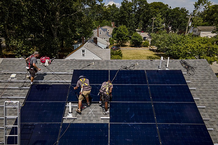 Employees of NY State Solar, a residential and commercial photovoltaic systems company, install an array of solar panels on a roof, Thursday, Aug. 11, 2022, in the Long Island hamlet of Massapequa, N.Y. Americans are less concerned now about how climate change might impact them personally — and about how their personal choices affect the climate than they were three years ago, according to a according to a June poll from The Associated Press-NORC Center for Public Affairs Research. (John Minchillo, AP File)