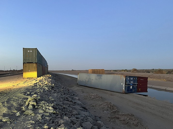 This photo provided of Univision Arizona shows empty shipping containers toppled over Sunday overnight on the Mexico-US international borderline in Yuma, Ariz., on Monday, Aug. 16, 2022. An effort by Arizona's Republican Gov. Doug Ducey to use shipping containers to close a 1,000-foot gap in the U.S.-Mexico border wall suffered a temporary setback over the weekend when two containers stacked on top of each were somehow toppled over. The stacked pair of containers were righted by early Monday morning. (Claudia Ramos/Univision Arizona via AP)