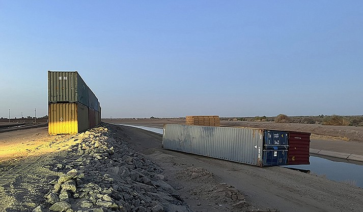 This photo provided of Univision Arizona shows empty shipping containers toppled over Sunday overnight on the Mexico-US international borderline in Yuma, Ariz., on Monday, Aug. 16, 2022. An effort by Arizona’s Republican Gov. Doug Ducey to use shipping containers to close a 1,000-foot gap in the U.S.-Mexico border wall suffered a temporary setback over the weekend when two containers stacked on top of each were somehow toppled over. The stacked pair of containers were righted by early Monday morning. (Claudia Ramos/Univision Arizona via AP)