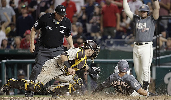 Washington Nationals’ César Hernández (1) slides into home plate on a hit by single by Victor Robles as San Diego Padres catcher Austin Nola, front left, attempts a tag during the seventh inning of a baseball game, Saturday, Aug. 13, 2022, in Washington. (AP Photo/Luis M. Alvarez)
