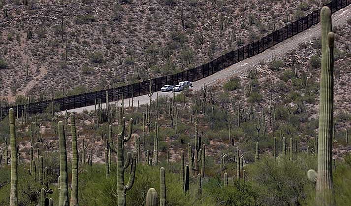 U.S. Customs and Patrol Patrol agents sit along a section of the international border wall that runs through Organ Pipe Cactus National Monument, Thursday, Aug. 22, 2019, in Lukeville, Ariz. The Border Patrol says one of its agents rescued an infant and a toddler Thursday, Aug. 25, 2022, who were left alone by migrant smugglers in the park. (AP Photo/Matt York, File)