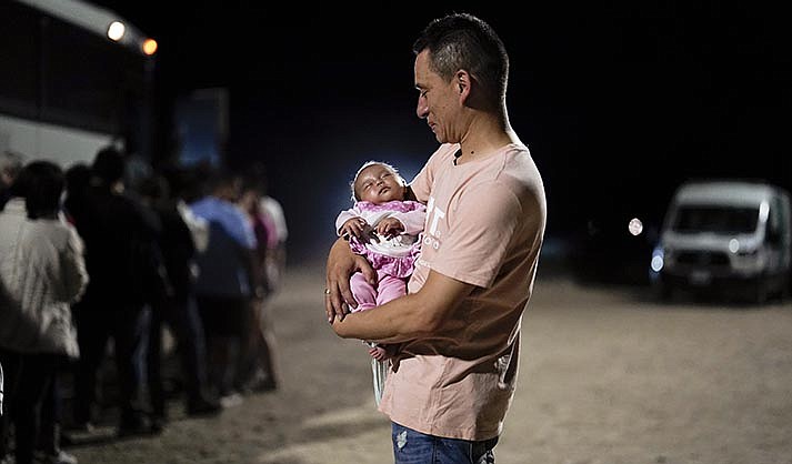 A migrant man from Colombia holds his baby daughter after crossing into the United States near the end of a border wall Tuesday, Aug. 23, 2022, near Yuma. (AP Photo/Gregory Bull)