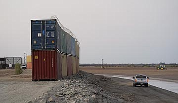 Border Patrol agents patrol along a line of shipping containers stacked near the border on Aug. 23, 2022, near Yuma. (AP Photo/Gregory Bull, File)