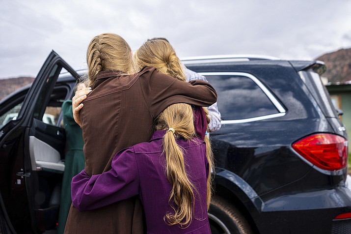 Three girls embrace before they are removed from the home of Samuel Bateman, following his arrest in Colorado City, Ariz., on Sept. 14, 2022. Seven were removed from the Bateman home, as well as two others from another house as part of the investigation. (Trent Nelson/The Salt Lake Tribune via AP)