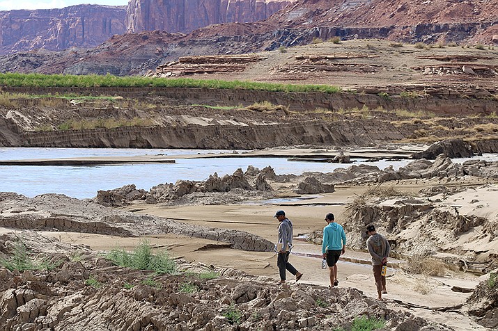 Mike DeHoff, Eric Balken and Pete Lefebvre walk near the mouth of White Canyon, a previously inundated area, now exposed as Lake Powell recedes. (Alex Hager/KUNC)