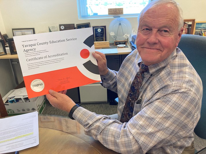 Yavapai County Superintendent Tim Carter, the head of the Yavapai County Education Service Agency, holds up the new accreditation report that will soon hang in the lobby of the agency office at 2970 Centerpointe East in Prescott. (Nanci Hutson/Courier)