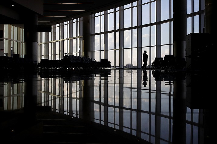 In this June 1, 2020 file photo, a woman looks through a window at a near-empty terminal at an airport in Atlanta. An influential health guidelines group says U.S. doctors should regularly screen adults for anxiety. It’s the first time the U.S. Preventive Services Task Force has recommended anxiety screening in primary care for adults without symptoms. The report released Tuesday, Sept. 20, 2022 is open for public comment until Oct. 17. (Charlie Riedel/AP, File)