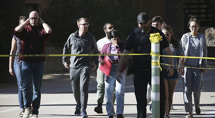 University of Arizona Police escort students from the scene of a shooting at the John W. Harshbarger Building on the University of Arizona campus in Tucson, Ariz., on Wednesday, Oct. 5, 2022. University of Arizona police say one person was shot and wounded on campus and authorities are searching for the suspect. (Rebecca Sasnett/Arizona Daily Star via AP)