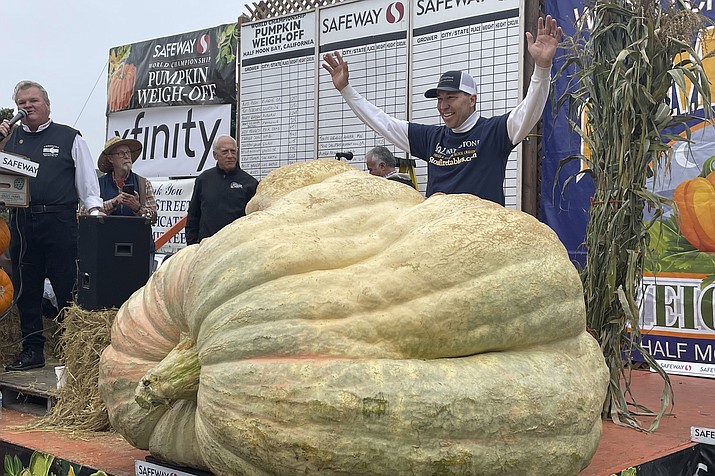 Travis Gienger from Anoka, Minn., stands behind his winning pumpkin at the 49th World Championship Pumpkin Weigh-Off in Half Moon Bay, Calif., Monday, Oct. 10, 2022. (Haven Daley/AP)