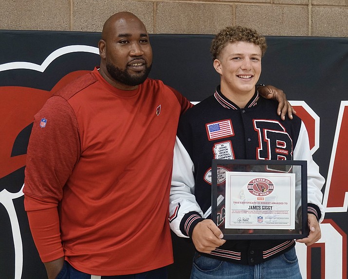 During a brief ceremonial event on Friday, Oct. 21, 2022, at the Bradshaw Mountain High School gym, Bradshaw Mountain football defensive end James Giggey, right, was awarded a plaque after the Arizona Cardinals chose him as their High School Player of the Week. Former Arizona Cardinals offensive tackle Brandon Keith, left, was one of the representatives in attendance to present him the award.(Aaron Valdez/Courier)