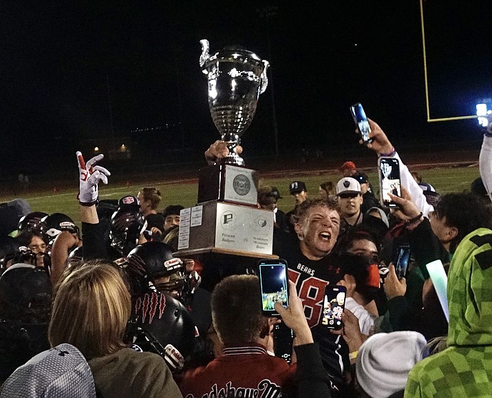 Bradshaw Mountain football defensive end James Giggey hoists the Esse Quam Videri trophy in a celebratory huddle after the team defeated Prescott 20-14 on Friday, Oct. 21, 2022, at Bob Pavlich Field in Prescott Valley. (Aaron Valdez/Courier)