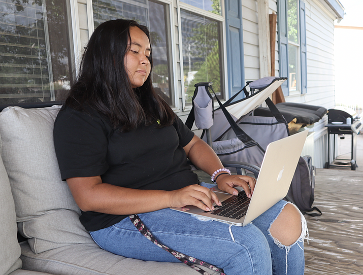 Brook Chavez looks at school work on her porch. The 16 year old lives in northeast Albuquerque, a few minutes away from La Cueva High School, where she’s in her junior year. (Photo/Bella Davis)