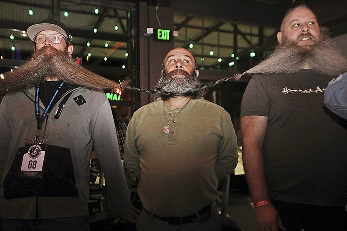 Men wait for the chain of their beards to be measured as part of their attempt at breaking the world's longest beard chain in the Guinness Book of World Records, Friday, Nov. 11, 2022, at The Gaslight Social in Casper, Wyo. (Lauren Miller/The Casper Star-Tribune via AP)
