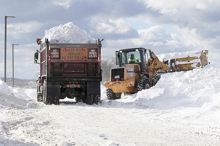 Crews truck snow in to dump in the parking lot of Erie Community College in Orchard Park in Erie County, N.Y., Sunday, Nov. 20, 2022. (Mark Mulville/The Buffalo News via AP)
