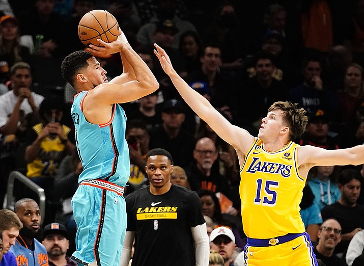 Phoenix Suns' Devin Booker shoots a three pointer against Los Angeles Lakers' Austin Reaves (15) during the first half of an NBA basketball game in Phoenix, Tuesday, Nov. 22, 2022. (Darryl Webb/AP)