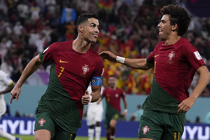 Portugal's Cristiano Ronaldo, left, celebrates with teammate Joao Felix after scoring from the penalty spot his side's opening goal against Ghana during a World Cup group H soccer match at the Stadium 974 in Doha, Qatar, Thursday, Nov. 24, 2022. (Manu Fernandez/AP)