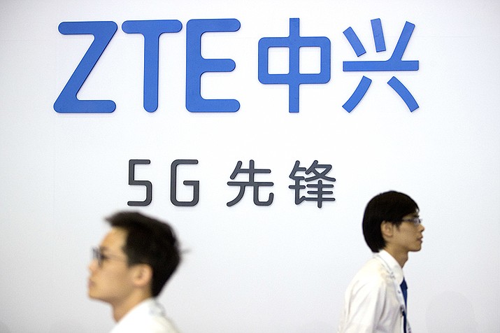 In this Sept. 26, 2018 file photo, visitors walk past a display from Chinese technology firm ZTE at the PT Expo in Beijing. The U.S. is banning the sale of communications equipment made by Chinese companies Huawei and ZTE and restricting the use of some China-made video surveillance systems, citing an “unacceptable risk” to national security. The 5-member Federal Communications Commission said Friday, Nov. 25, 2022 it has voted unanimously to adopt new rules that will block the importation or sale of certain technology products that pose security risks. (Mark Schiefelbein, AP file)