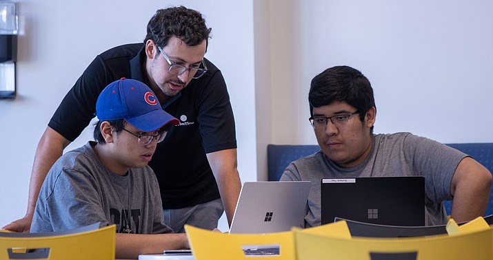 Alec Evans, assistant director of data science for DriveTime, guides Miguel Fernandez, 16, left and Zyron Hilsee, 16, as they work to create a chatbot through Microsoft Azure during the Mark Cuban Foundation AI Boot Camp at the DriveTime corporate office in Tempe in this Oct. 22 photo. (Justin Spangenthal/Cronkite News)