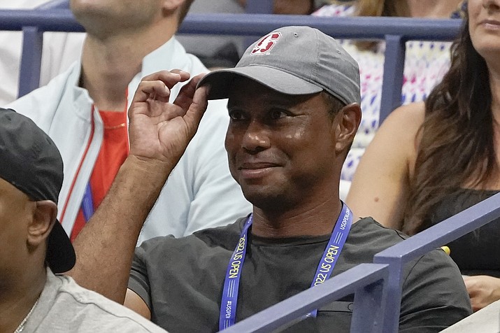 Tiger Woods tips his hat to the crowd during a match between Serena Williams and Anett Kontaveit, of Estonia, in the second round of the U.S. Open tennis championships, Wednesday, Aug. 31, 2022, in New York. Woods has won the Player Impact Program on the PGA Tour despite playing only three times. He is likely to play three unofficial events in December.(John Minchillo/AP, File)