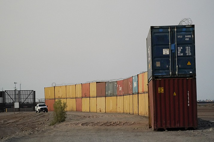 Border Patrol agents patrol along a line of shipping containers stacked near the border on Aug. 23, 2022, near Yuma, Ariz. The federal government is seeking the dismissal of a lawsuit by Arizona governor Doug Ducey arguing the state has the right to erect the containers. (Gregory Bull, AP File)