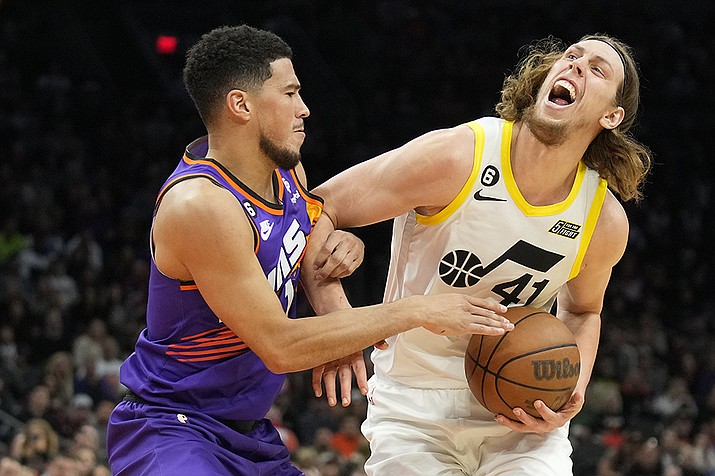 Utah Jazz forward Kelly Olynyk (41) gets fouled by Phoenix Suns guard Devin Booker during the first half of an NBA basketball game, Saturday, Nov. 26, 2022, in Phoenix. (AP Photo/Rick Scuteri/AP)