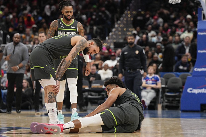 Minnesota Timberwolves guard Austin Rivers, left, checks on center Karl-Anthony Towns (32) after he got hurt during the second half of a game against the Washington Wizards, Monday, Nov. 28, 2022, in Washington. (Jess Rapfogel/AP)