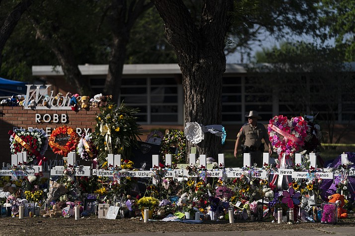 Flowers and candles are placed around crosses on May 28, 2022, at a memorial outside Robb Elementary School in Uvalde, Texas, to honor the victims killed in the school shooting a few days prior. Victims of the Uvalde school shooting that left 21 people dead have filed a lawsuit seeking $27 billion against local and state police, the city and other school and law enforcement officials for failing to follow active shooter protocol because authorities waited more than an hour to confront the attacker inside a fourth-grade classroom, according to court documents. (Jae C. Hong/AP, File)