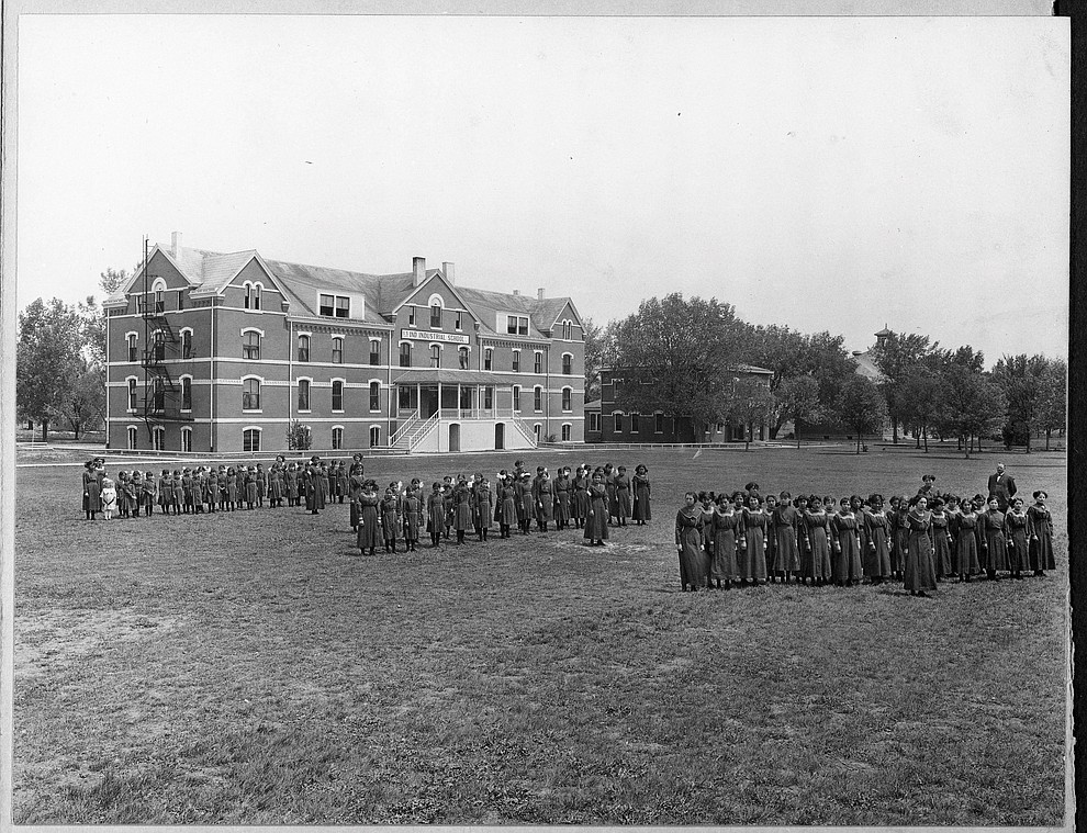 In this undated photo provided by National Archives, some students at the former Genoa Indian Industrial School in Genoa, Nebraska line up outside the school. Researchers are now trying to locate the bodies of more than 80 Native American children buried near the school in central Nebraska. For decades, the location of the student cemetery has been a mystery, lost over time after the school closed in 1931 and memories faded of the once-busy campus that sprawled over 640 acres in the tiny community of Genoa. (National Archives via AP)
