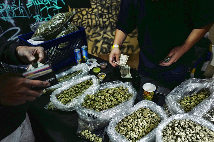 A vendor makes change for cannabis sale at a Los Angeles marketplace in this photo from 2020, when Arizona voters legalized recreational use of marijuana. Since then, cannabis sales in Arizona have surged to an estimated $1.6 billion, second only to California, but production in the state still lags. (Richard Vogel/AP/Shutterstock)