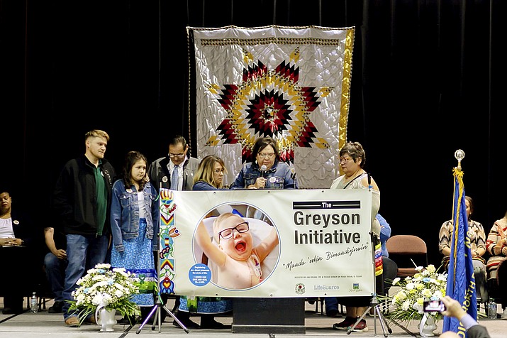 In this photo provided by LifeSource, Joan Azure, the grandmother of Greyson Parisien, center, speaks at an event in Belcourt, N.D., on Monday, Nov. 14, 2022, where the Turtle Mountain Band of Chippewa Indians unveiled an identification card that has a spot to designate organ donation. Tribal member Greyson Parisien, who had a heart transplant, inspired the change. The Turtle Mountain Band of Chippewa is the first tribal nation to offer donor registration on tribal identification cards. (Mike Hutto/LifeSource via AP)