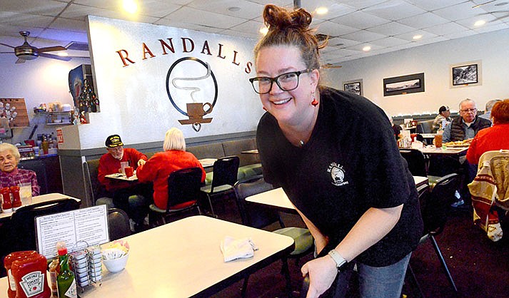 Becky Bierwas straightens chairs after bussing a table at Randall’s Restaurant on Dec. 23, 2022. (VVN/Vyto Starinskas)