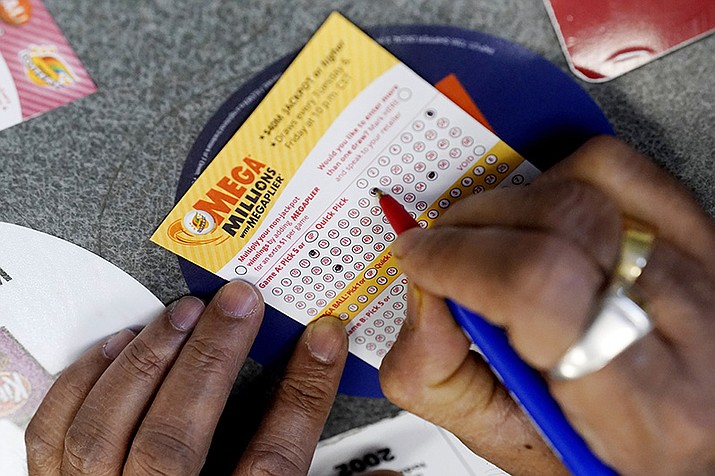 A customer fills out a Mega Millions lottery ticket at a convenience store in Northbrook, Ill., on Jan. 6, 2021. The top prize increased to $785 million ahead of the next drawing Tuesday night. (AP Photo/Nam Y. Huh, File)